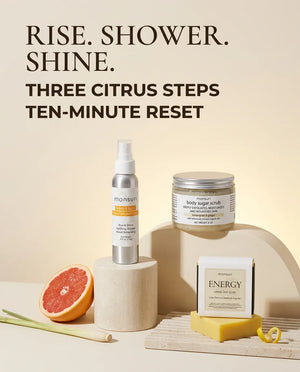 Rise, shower, shine - three citrus steps and a ten-minute reset, the spray, the scrub and the soap bar arranged on pale plinths with grapefruit and lemongrass