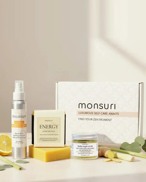 The Energizing Shower Ritual set in front of the Monsuri gift box - the 4 oz CITRUS energizing spray, the ENERGY lemon zest scrub soap bar and the 2.5 oz lemongrass and ginger body sugar scrub, with fresh lemon, ginger root and lemongrass stalks