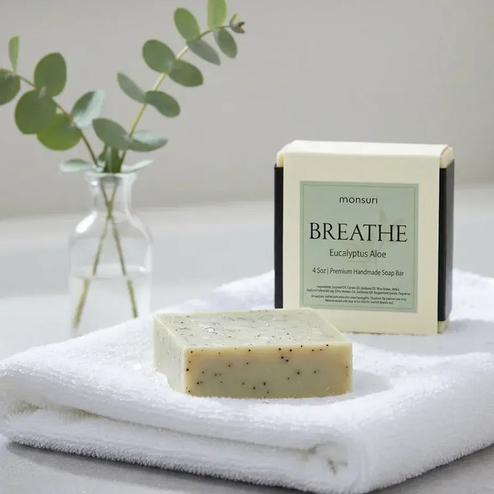 Monsuri BREATHE eucalyptus aloe soap bar on a folded towel with the box and a eucalyptus sprig — natural eucalyptus soap bar ingredients