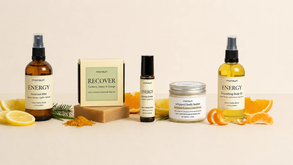 The five pieces of the Mom Energy Boost set lined up on a warm backdrop with lemon, orange and ground turmeric: the ENERGY hydrosol mist at 3.3 fl oz, the RECOVER turmeric, honey and orange soap at 4.5oz, the essential oil roller at 0.33 fl oz, the lemongrass and rosemary whipped body butter at 1.75oz, and the ENERGY nourishing body oil at 3.3 fl oz.