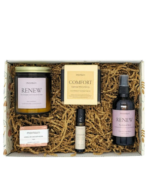 The sympathy set nested in the Monsuri kraft gift box on shredded kraft fill - the RENEW candle, the COMFORT oatmeal soap, the bath bomb, the roller and the rose hydrosol mist