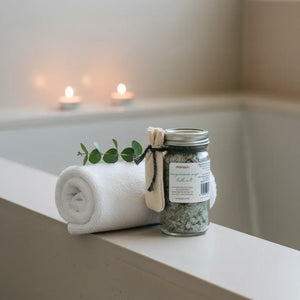 Jar of Magnesium Sage Bath Salts with Muslin Pouch resting on a Bathtub Edge