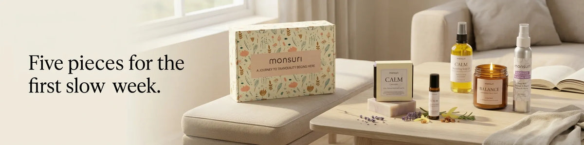 Five pieces for the first slow week - the botanical gift box on a living-room table with the lit palo santo candle, the CALM soap, the body oil, the roller and the lavender mist