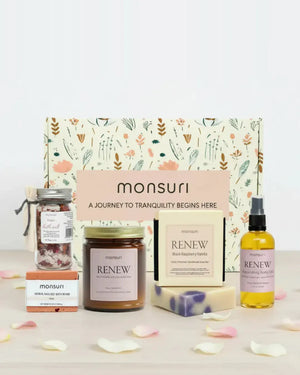 Romantic spa gift set arranged in front of the Monsuri botanical kraft gift box - rose bath salt jar 1.5 oz, herbal-infused rose bath bomb 4 oz, RENEW rose and sandalwood candle 7 oz, black raspberry vanilla soap bar 4.5 oz and nourishing body oil 3.3 fl oz, scattered with fresh rose petals