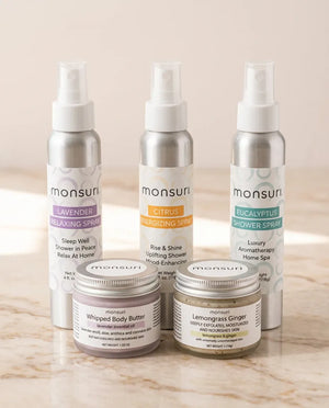 Monsuri whipped body butter and lemongrass ginger sugar scrub open side by side on a ceramic tray with lavender sprigs.