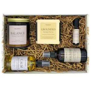 Aromatherapy stress gift set palo santo candle burning next to essential oil roller and meditation mist for daily stress relief ritual