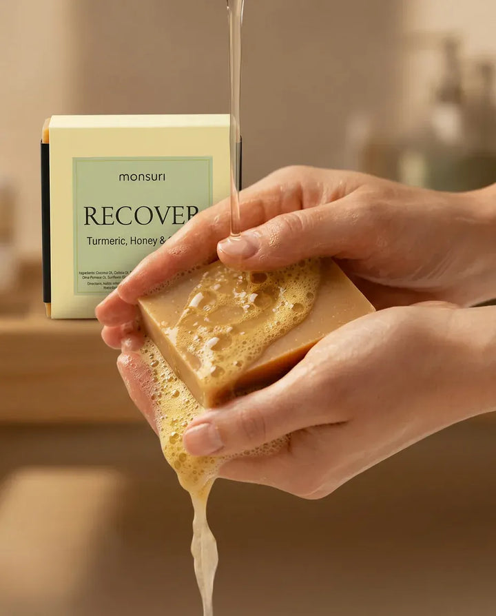 Hands lathering the Turmeric Honey & Orange soap bar under water — natural golden soap bar in use