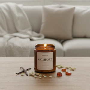 Amber glass Comfort Candle with warm vanilla and jasmine notes styled on sofa-side table for calming home décor
