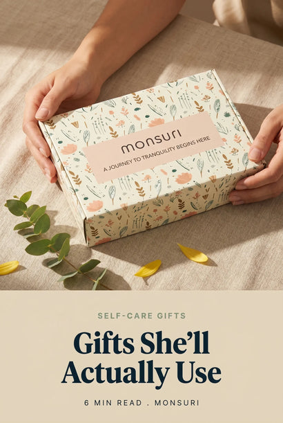 Self-care gifts for women — a Monsuri botanical gift box held in two hands on linen with eucalyptus (editorial cover).