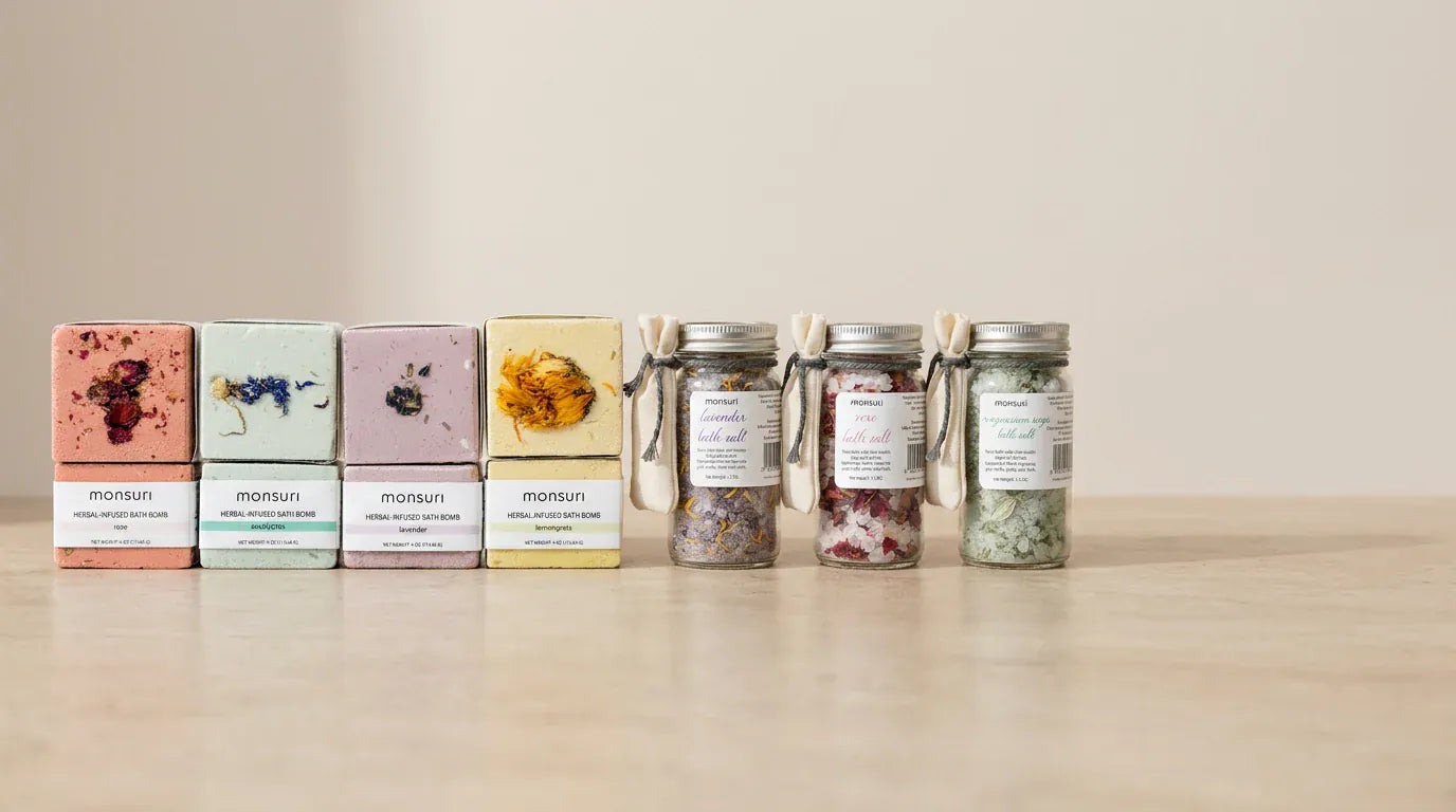 All seven pieces lined up along a stone ledge: the rose, eucalyptus, lavender and lemongrass bath bombs in their boxes, followed by the lavender, rose and magnesium and sage herbal bath salt jars.