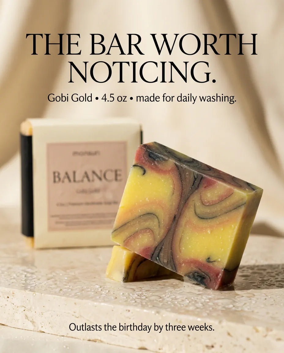 The bar worth noticing - Gobi Gold, 4.5 oz, made for daily washing, the marbled soap bar propped against its box on wet travertine: outlasts the birthday by three weeks