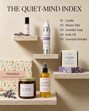 The quiet-mind index - all five pieces on stone shelves with the botanical gift box: 01 candle, 02 shower mist, 03 lavender soap, 04 body oil, 05 essential oil roller