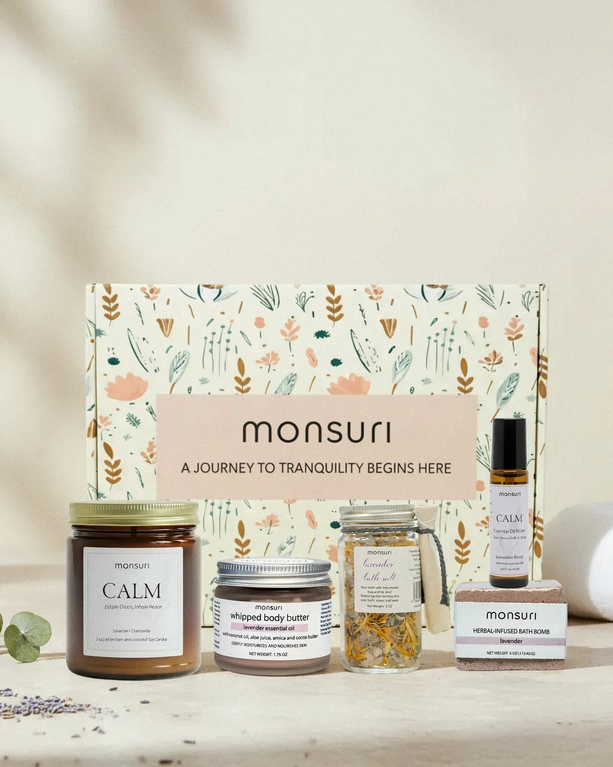The Deep Relaxation lavender gift set in front of its botanical kraft gift box printed "A journey to tranquility begins here": the CALM lavender chamomile candle, the lavender whipped body butter, the lavender bath salt jar, the CALM essential oil roller and the herbal-infused lavender bath bomb.