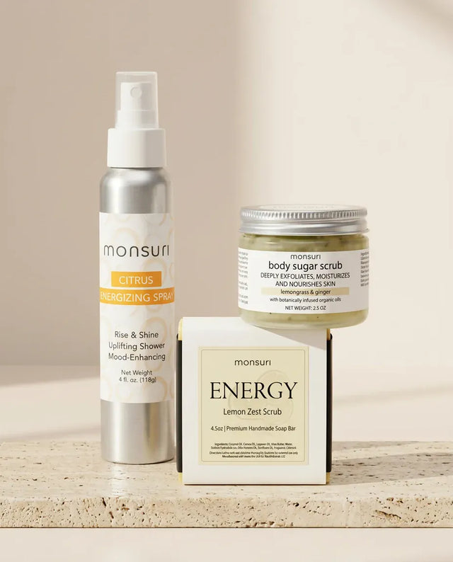 All three pieces on a travertine ledge - the 4 oz CITRUS energizing spray, the 2.5 oz lemongrass and ginger body sugar scrub and the ENERGY lemon zest scrub soap bar