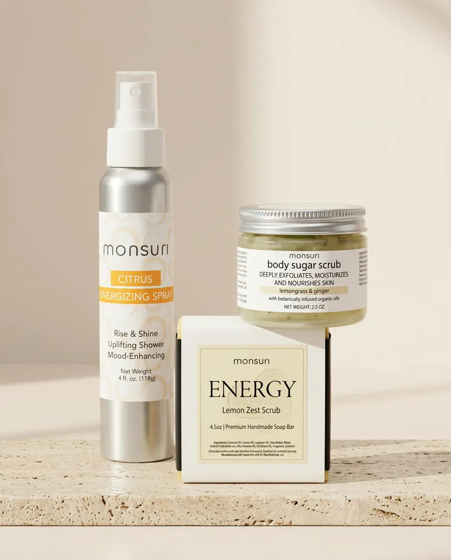 All three pieces on a travertine ledge - the 4 oz CITRUS energizing spray, the 2.5 oz lemongrass and ginger body sugar scrub and the ENERGY lemon zest scrub soap bar