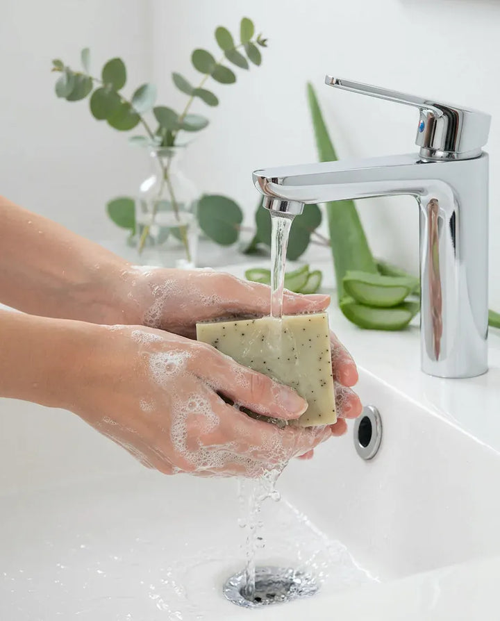 Hands lathering the Eucalyptus Aloe soap bar under a faucet — natural clarity soap bar in use