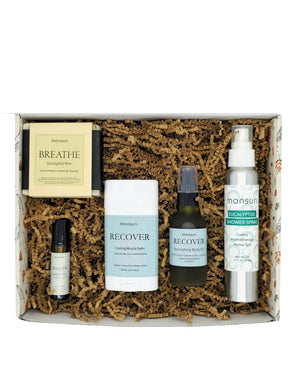 The Get Well Soon set open in the Monsuri kraft gift box on shredded kraft fill - the BREATHE soap, the cooling muscle balm, the RECOVER body oil, the eucalyptus shower spray and the roller