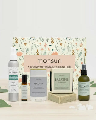 All five pieces of the Monsuri Get Well Soon set - the 4 oz eucalyptus shower spray, the 4.5 oz eucalyptus aloe soap bar, the 2 oz RECOVER muscle-reset body oil, the 2.3 oz cooling muscle balm stick and the BREATHE clarity essential oil roller