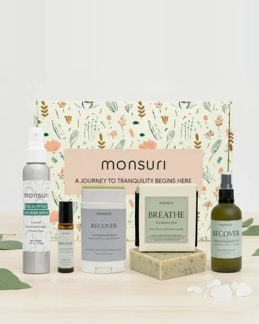 All five pieces of the Monsuri Get Well Soon set - the 4 oz eucalyptus shower spray, the 4.5 oz eucalyptus aloe soap bar, the 2 oz RECOVER muscle-reset body oil, the 2.3 oz cooling muscle balm stick and the BREATHE clarity essential oil roller