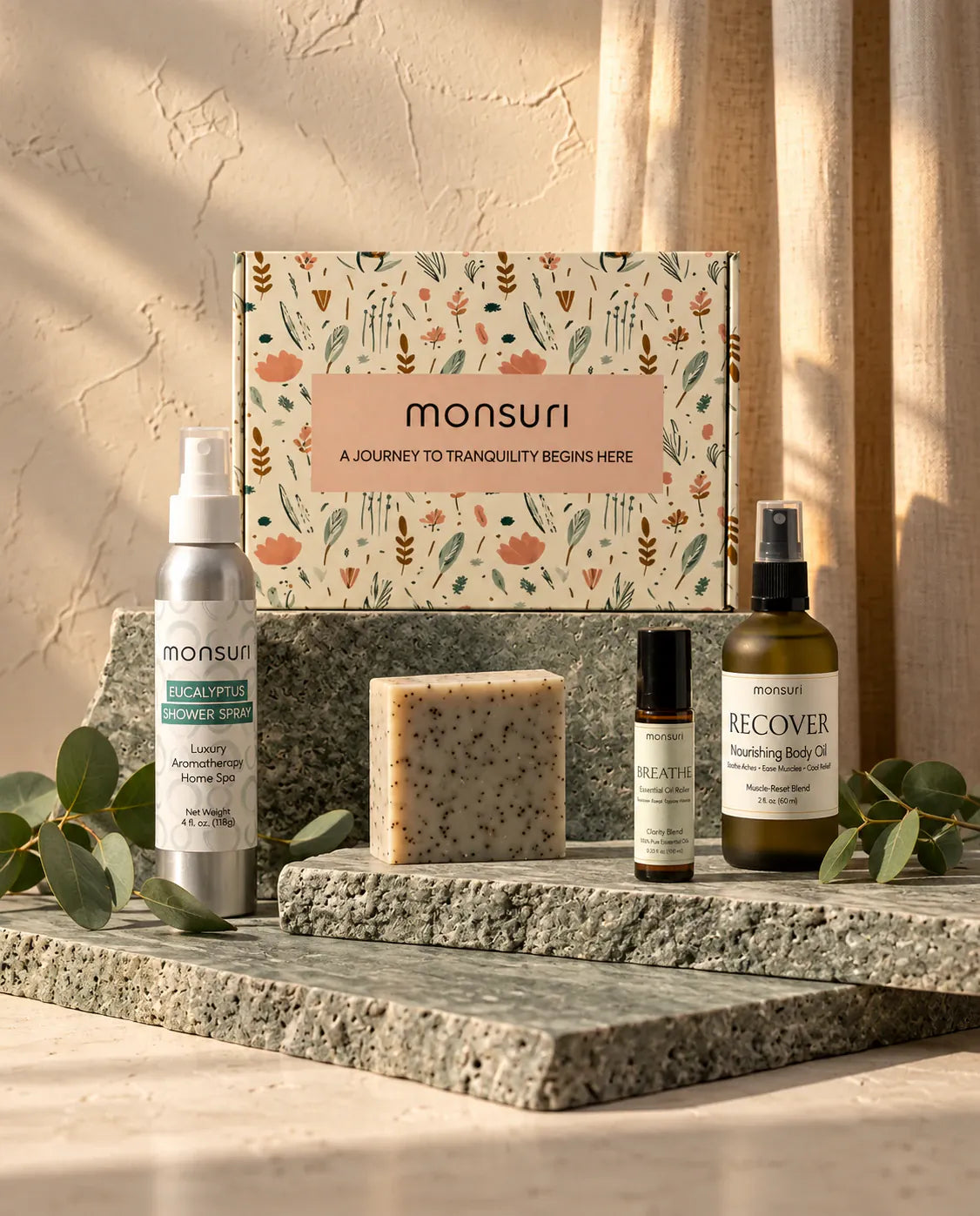 The five Get Well Soon pieces arranged on stone plinths in front of the Monsuri botanical gift box with eucalyptus