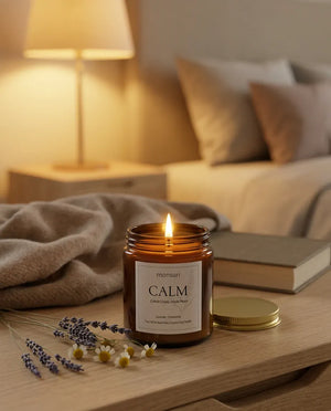 Monsuri CALM lavender chamomile candle lit on a sunlit windowsill table next to a teacup, potted plant, and a notebook and pen.