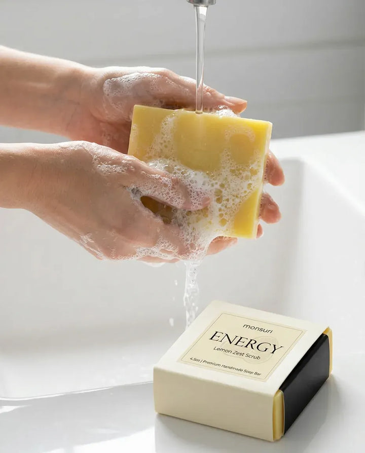 Hands lathering the Lemon Zest Scrub soap bar under a faucet — natural exfoliating soap bar in use