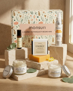 The Little Box of Sunshine set arranged on stone plinths in front of the Monsuri botanical gift box, the ENERGY lemon zest soap propped against it