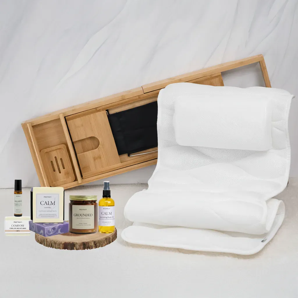 Self-care Sunday routine — the Monsuri Home Spa Day Kit laid out for an at-home spa Sunday: bamboo bath tray, full-body bath pillow, calm body oil, vanilla bath bomb, mahogany candle, and eucalyptus roller arranged in soft natural light