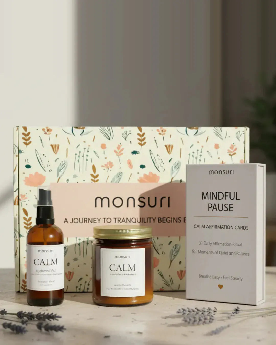 Mindful Pause relaxation gift set in front of the Monsuri botanical gift box - CALM lavender hydrosol mist in amber glass, the CALM lavender and chamomile candle with a 45 hour burn, and the MINDFUL PAUSE deck of 31 calm affirmation-ritual cards, with dried lavender