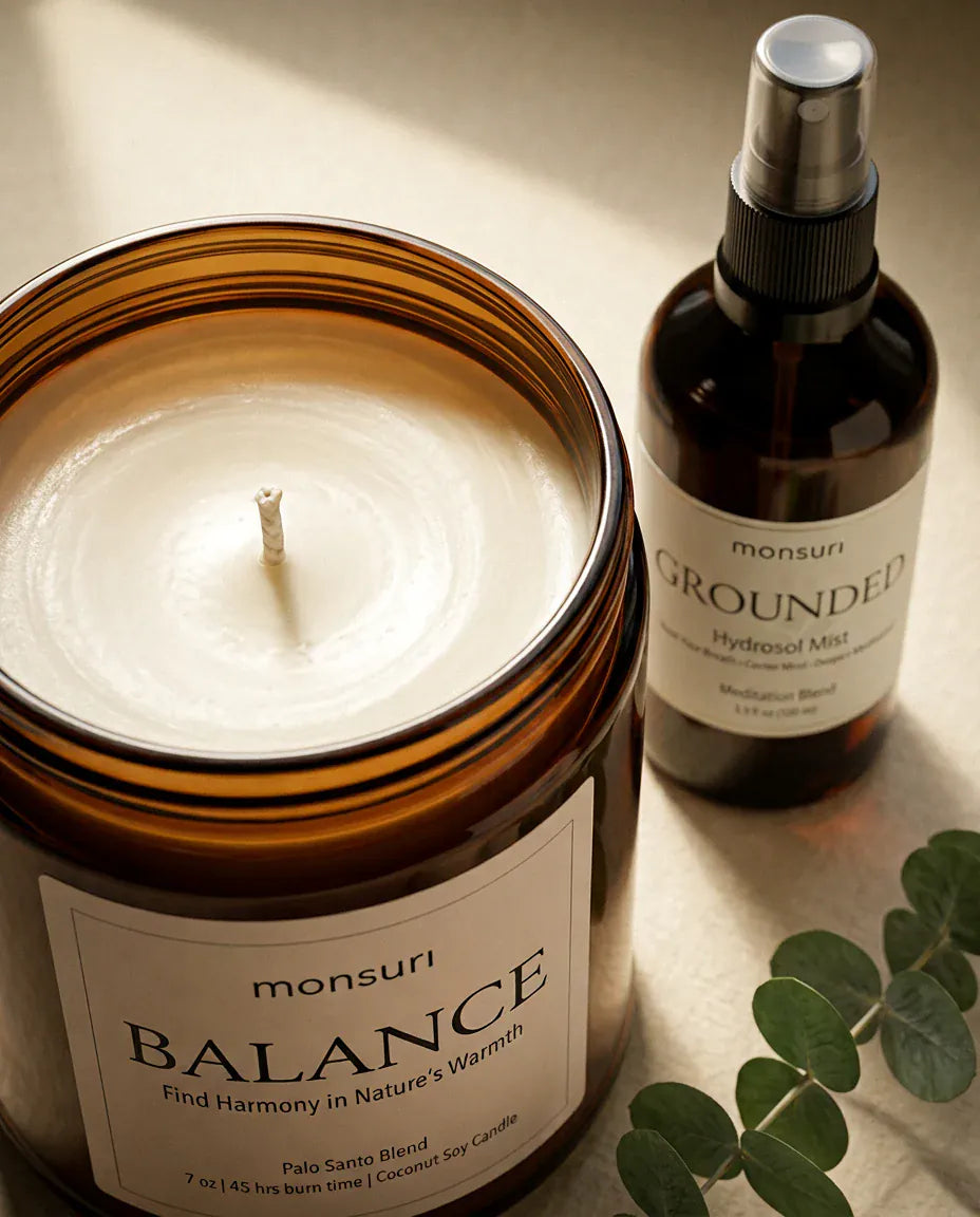 Close overhead of the BALANCE palo santo candle showing its full wax pool and single wick, labelled 7 oz, 45 hours burn time, coconut soy candle, with the GROUNDED hydrosol mist and a eucalyptus sprig behind it.