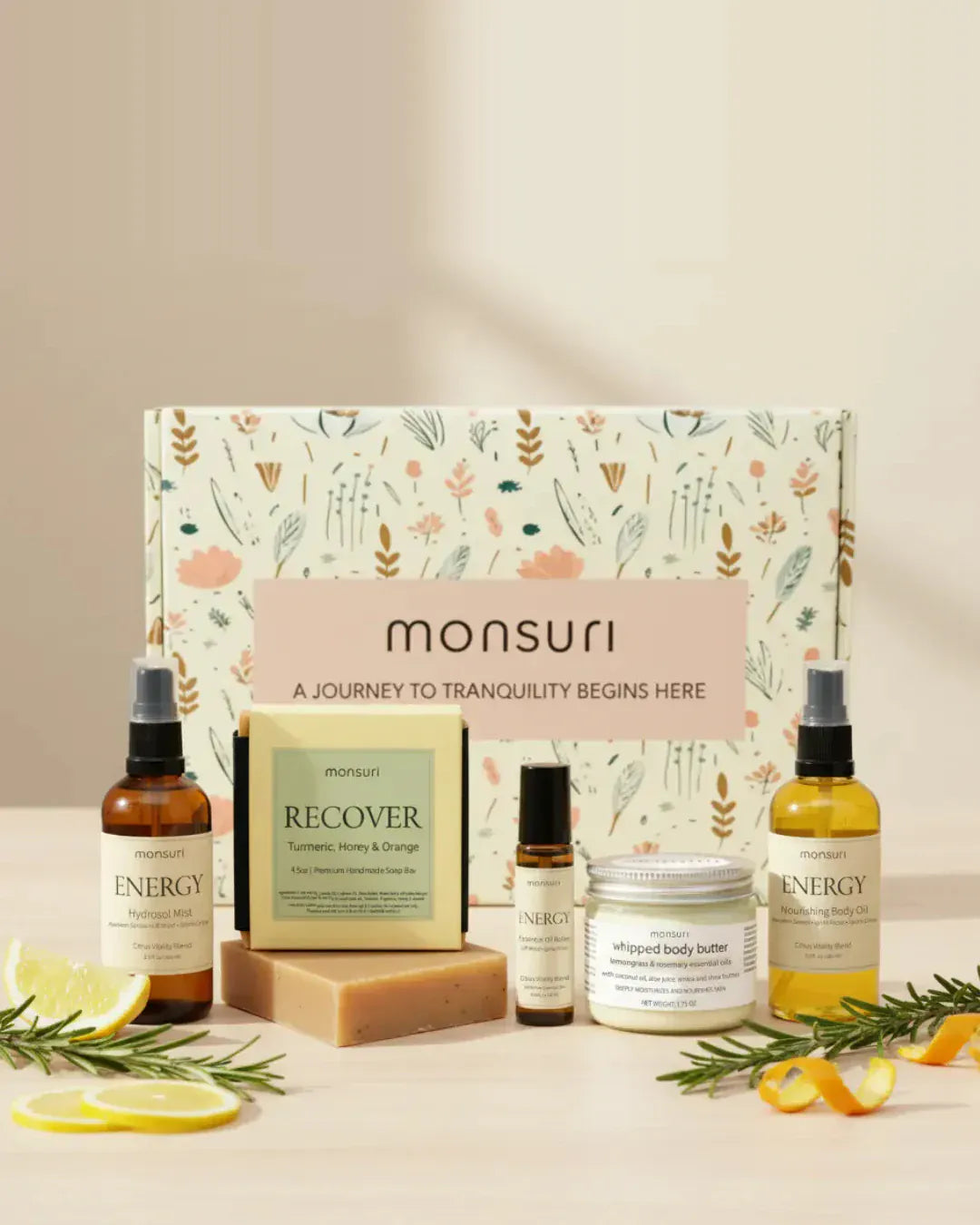 Energizing gifts for mom: the five-piece Monsuri set with citrus hydrosol mist, turmeric honey and orange soap, energy roller, whipped body butter and nourishing body oil in front of the botanical kraft gift box