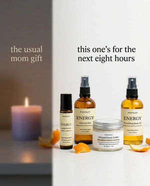 The usual mom gift is a lavender candle for winding down; this one is built for the next eight hours instead — the energy roller, the citrus hydrosol mist, the whipped body butter and the nourishing body oil lit bright against the dim candle.