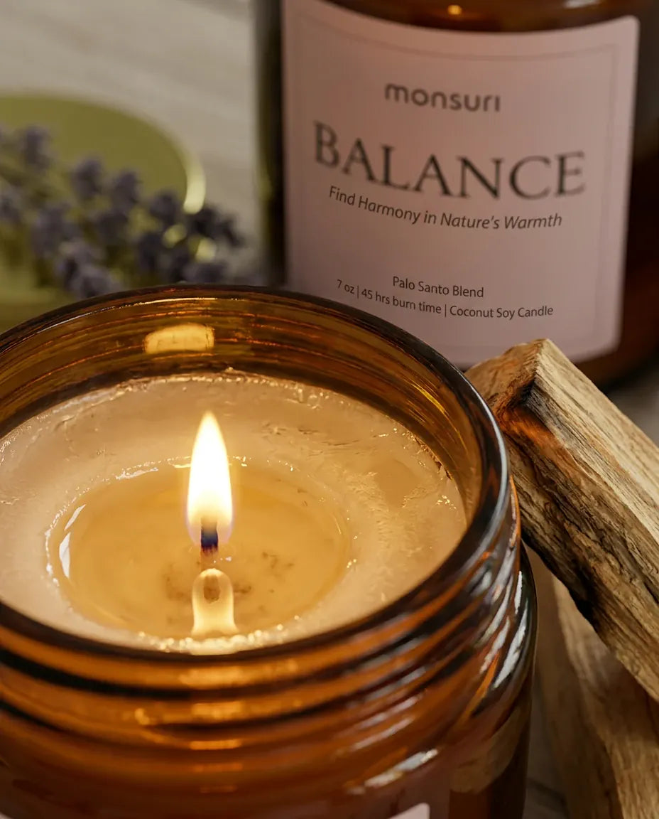 Close-up of the Monsuri BALANCE palo santo candle's coconut-soy wax pool and cotton wick burning evenly to the glass edge.