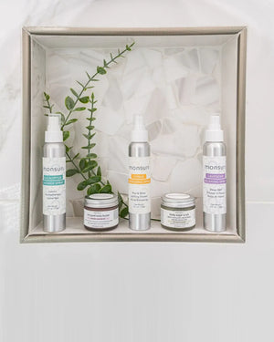 The Monsuri Sensory Symphony gift set presented in a white display box - the eucalyptus, citrus and lavender 4 oz shower sprays standing behind the whipped body butter and lemongrass ginger sugar scrub jars, with a eucalyptus sprig