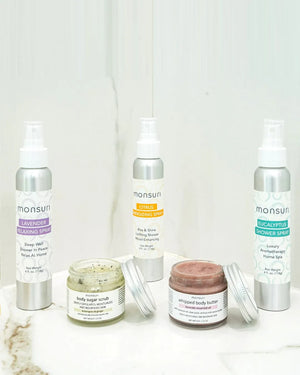 All five pieces of the Monsuri Sensory Symphony aromatherapy gift set on white marble - the 4 oz LAVENDER relaxing, CITRUS energizing and EUCALYPTUS shower sprays with the 1.75 oz whipped body butter and the 2.5 oz lemongrass ginger body sugar scrub, jars open