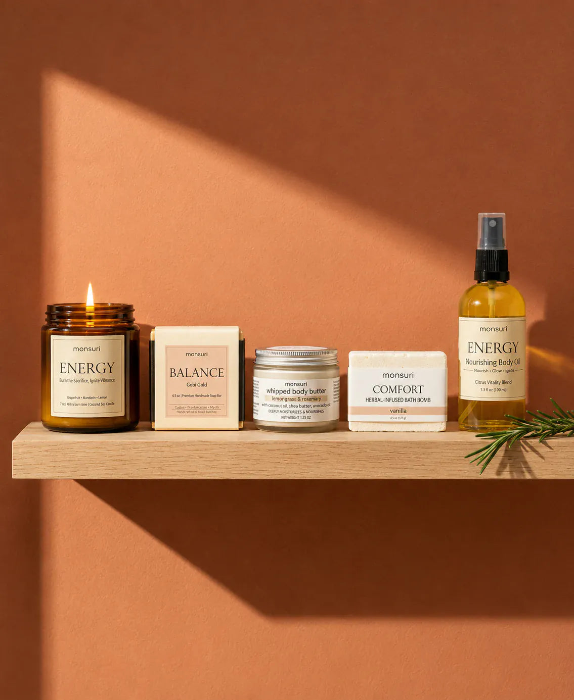 The five pieces arranged along a floating oak shelf against a terracotta wall, a shaft of afternoon light falling across them and a sprig of rosemary at one end.