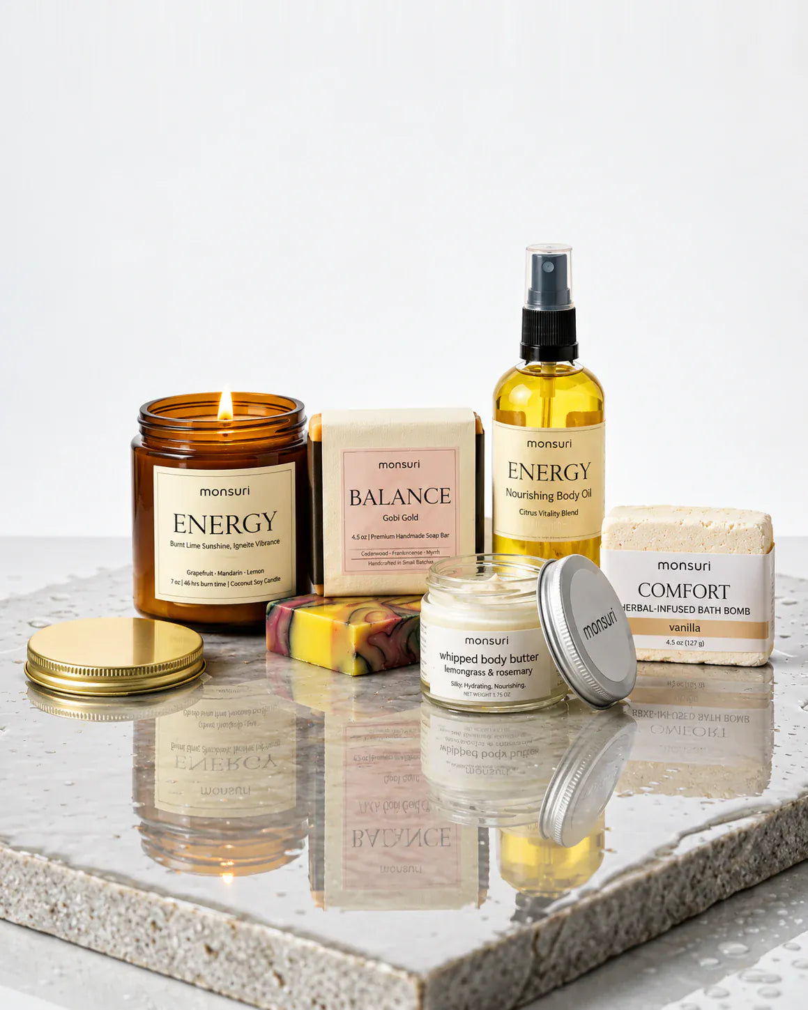 The five pieces on a wet stone slab reflecting them back, the candle lit and its gold lid laid flat, against a pale grey wall.