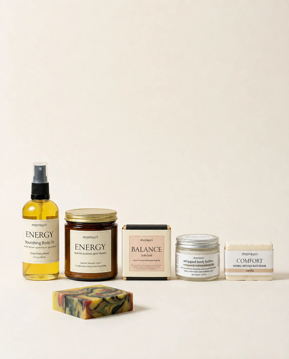 All five Bestie Boost pieces lined up on a cream backdrop — the ENERGY body oil, the ENERGY grapefruit candle, the boxed BALANCE Gobi Gold soap, the whipped body butter and the COMFORT vanilla bath bomb, with the marbled soap bar unwrapped in front.