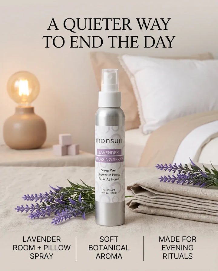 Monsuri lavender aromatherapy spray on a nightstand beside a lit lamp and fresh lavender sprigs, styled for a quieter way to end the day.