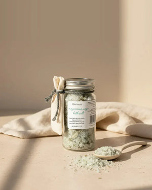 The Monsuri magnesium sage bath salts jar, 1.5 oz, with its wooden spoon and a scatter of salts on linen