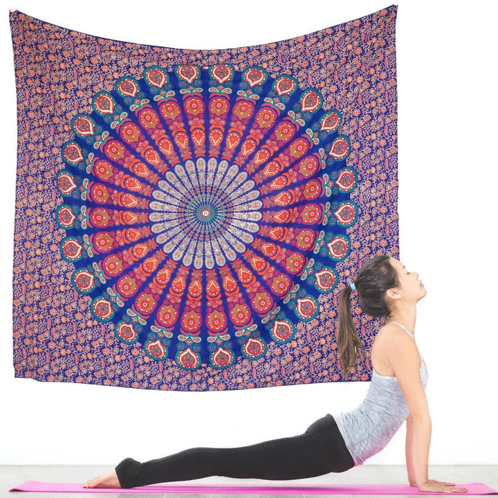 Red and blue mandala tapestry hung as a wall hanging behind a bed